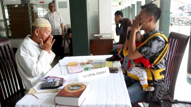 Umat muslim melaksanakan pembayaran Zakat Fitrah di masjid Jami Nurul Islam, Pangkalan Jati, Depok, Jawa Barat, Selasa (4/6). [Suara.com/Arief Hermawan P]