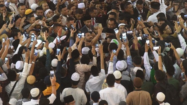 Presiden Joko Widodo (tengah) menerima ajakan swafoto warga usai melakukan Shalat Id di Masjid Istiqlal, Jakarta, Rabu (5/6). [ANTARA FOTO/Akbar Nugroho Gumay]