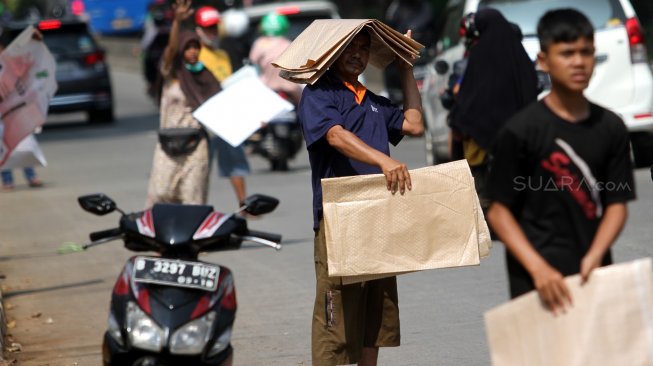 Pedagang menawarkan tikar kepada warga yang melintas di Jalan RM Harsono, Jakarta Selatan, Kamis (6/6).  [Suara.com/Arief Hermawan P]