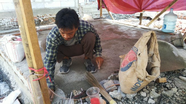 Salah satu warga kampung Bandan sedang membangun kembali rumahnya. (Suara.com/Stephanus Aranditio) 