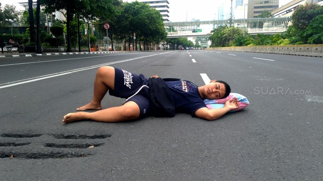 Warga berfoto di Jalan MH Thamrin yang tampak sepi saat hari ketiga lebaran, Jumat (7/6). [Suara.com/Oke Atmaja]