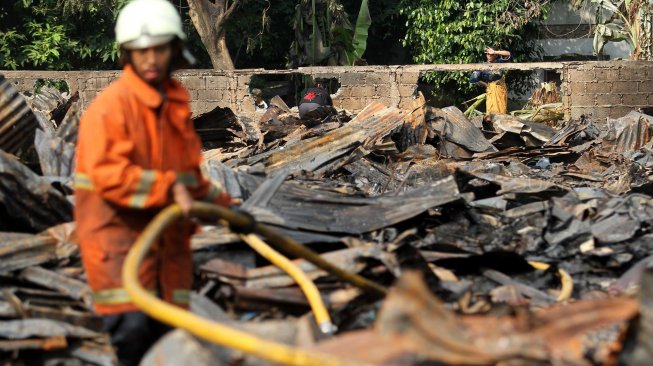 Petugas pemadam kebakaran (damkar) memadamkan sisa bara api usai terjadi kebakaran yang menghanguskan lapak pemulung di dekat Terminal Pasar Minggu, Jakarta, Sabtu (8/6). [Suara.com/Arief Hermawan P]