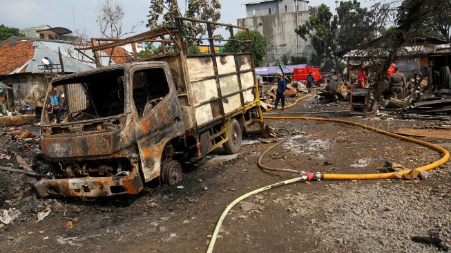 Petugas pemadam kebakaran (damkar) memadamkan sisa bara api usai terjadi kebakaran yang menghanguskan lapak pemulung di dekat Terminal Pasar Minggu, Jakarta, Sabtu (8/6). [Suara.com/Arief Hermawan P]