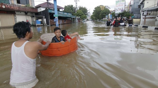 Seseorang warga mendorong drum berisi anak-anaknya yang bermain banjir di kawasan Jalan dr Soetomo di Samarinda, Kalimantan Timur, Senin (10/6). ANTARA FOTO/Kirana Larasati