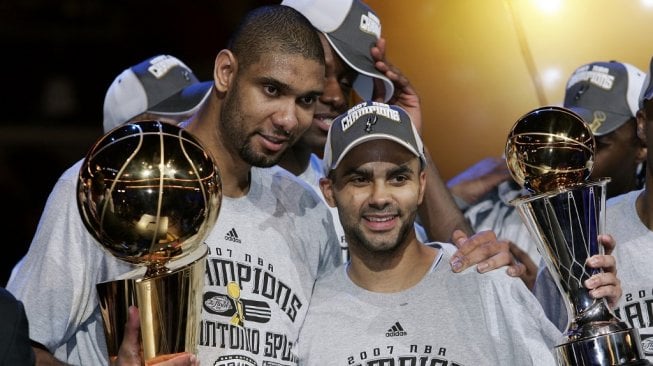 Tony Parker (kanan) mengangkat trofi MVP NBA Finals 2007 bersama rekannya di San Antonio Spurs, Tim Duncan, yang memegang trofi NBA. [AFP/Jeff Haynes]