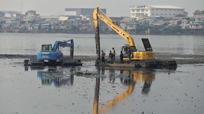 Petugas Pemprov DKI Jakarta melakukan pengerukan lumpur di Waduk Pluit, Jakarta, Selasa (11/6). [Suara.com/Muhaimin A Untung]