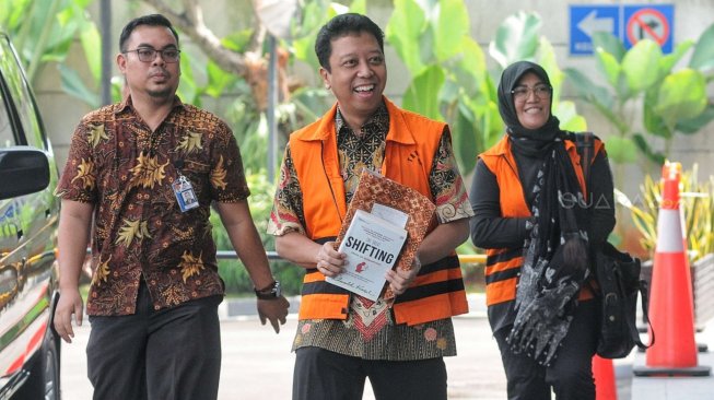 Eks Ketua Umum PPP Romahurmuziy menutupi tangan terborgol dengan buku saat menjalani pemeriksaan di Gedung KPK, Jakarta, Rabu (12/6). [Suara.com/Muhaimin A Untung]