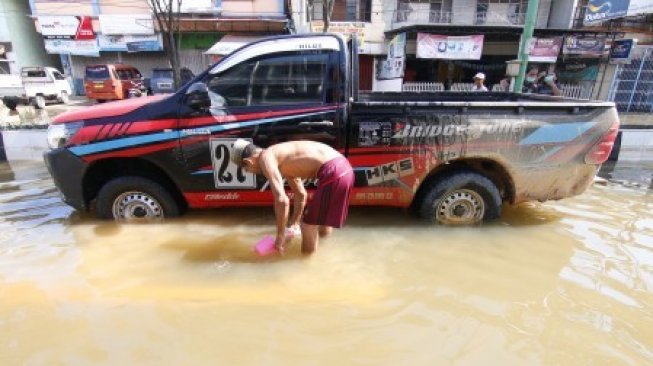 Seorang warga mencuci mobil di kawasan Jalan A Yani yang terendam banjir di Samarinda, Kalimantan Timur, Rabu (12/6/2019). Banjir yang melanda Kota Samarinda selama enam hari terakhir tersebut kini mulai surut dan masyarakat setempat sudah mulai kembali beraktivitas [ANTARA FOTO/Kirana Larasati/jhw/foc].