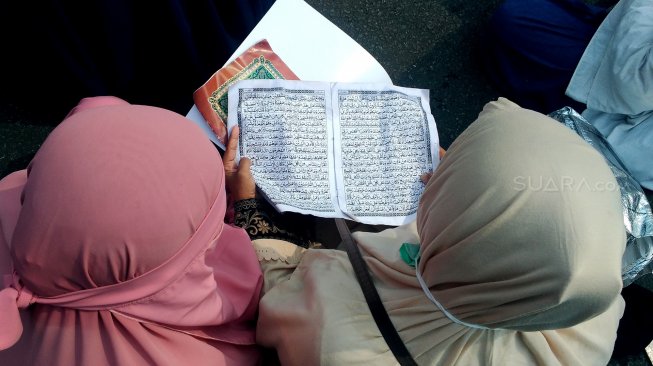 Sejumlah emak-emak membaca Alquran di sela sidang sengketa Pilpres yang digelar di Mahkamah Konstitusi, Jakarta, Jumat (14/6). [Suara.com/Oke Atmaja]