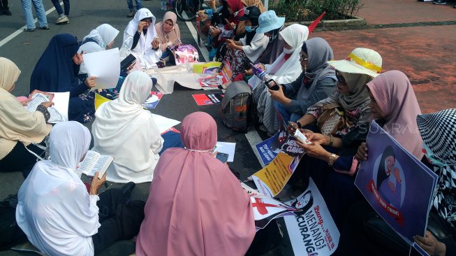 Sejumlah emak-emak membaca Alquran di sela sidang sengketa Pilpres yang digelar di Mahkamah Konstitusi, Jakarta, Jumat (14/6). [Suara.com/Oke Atmaja]