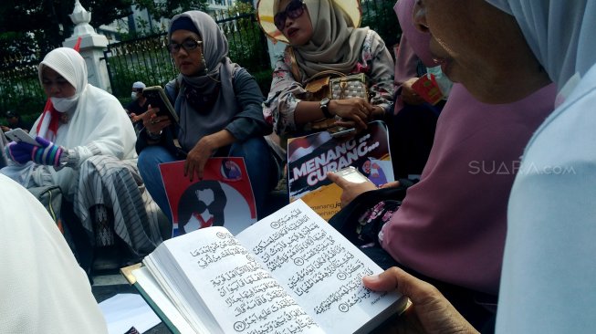 Sejumlah emak-emak membaca Alquran di sela sidang sengketa Pilpres yang digelar di Mahkamah Konstitusi, Jakarta, Jumat (14/6). [Suara.com/Oke Atmaja]