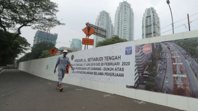 Sejumlah pekerja beraktifitas di samping proyek kereta Light Rail Transit (LRT) di Jalan Setiabudi Tengah, Jakarta Pusat, Senin (17/6). [Suara.com/Muhaimin A Untung]