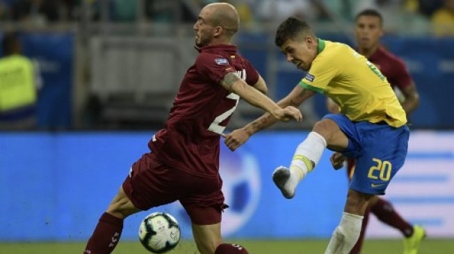 Striker Brazil Roberto Firmino (kanan) melepaskan tendangan coba dihadang pemain Venezuela Mikel Villanueva di Copa America 2019. Juan MABROMATA / AFP