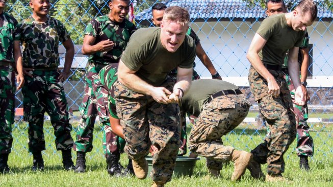 Prajurit Marinir Amerika Serikat dari United States Marine Corps/United States Marine Pacific (US MARFORPAC) mengikuti lomba memasukkan belut kedalam botol di lapangan Brigif 2 Marinir Gedangan, Sidoarjo, Jawa Timur, Jumat (21/6). [ANTARA FOTO/Umarul Faruq]