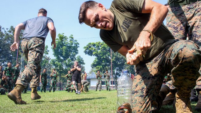 Prajurit Marinir Amerika Serikat dari United States Marine Corps/United States Marine Pacific (US MARFORPAC) mengikuti lomba memasukkan belut kedalam botol di lapangan Brigif 2 Marinir Gedangan, Sidoarjo, Jawa Timur, Jumat (21/6). [ANTARA FOTO/Umarul Faruq]