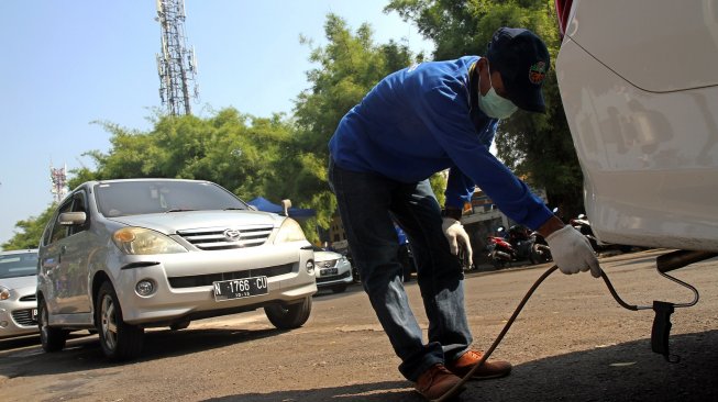 Petugas melakukan pemerikasaan emisi gas buang kendaraan di halaman parkir Taman Makam Pahlawan (TMP) Kalibata, Jakarta, Selasa (25/6). [Suara.com/Arief hermawan P]