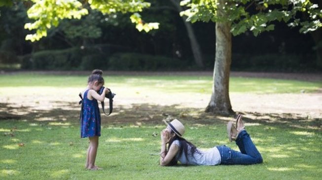 Anak sedang belajar fotografi dengan model perempuan dewasa di ruang terbuka. (Shutterstock)