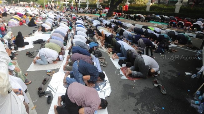 Sejumlah peserta aksi melakukan salat Ashar berjamaah di kawasan Gedung Mahkamah Konstitusi, Jakarta, Kamis (27/6). [Suara.com/Muhaimin A Untung]
