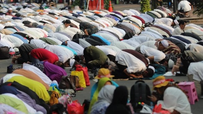 Sejumlah peserta aksi melakukan salat Ashar berjamaah di kawasan Gedung Mahkamah Konstitusi, Jakarta, Kamis (27/6). [Suara.com/Muhaimin A Untung]
