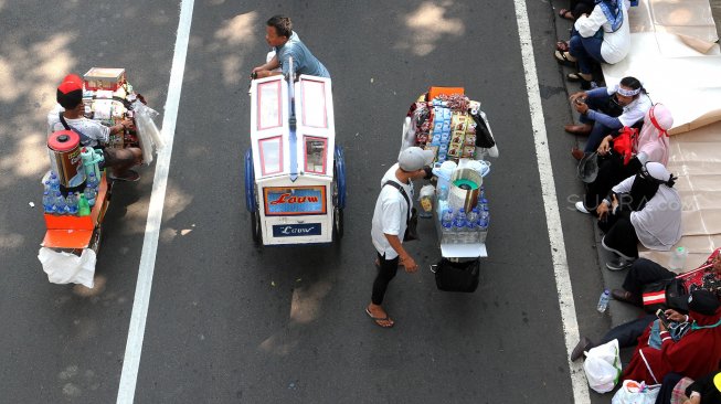 Sejumlah pedagang berjualan diantara massa yang berkumpul di kawasan Patung Kuda, Monas, Jakarta, Kamis (27/6). [Suara.com/Arief Hermawan P]