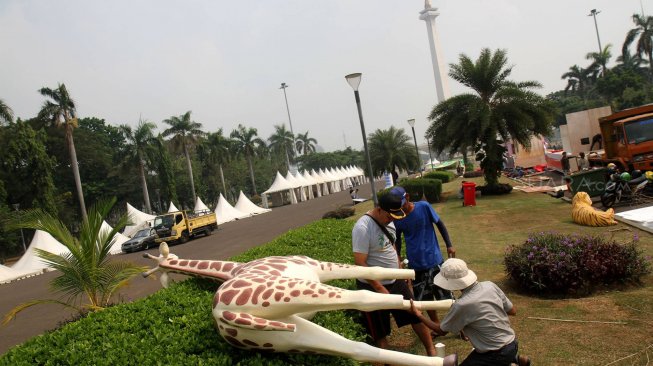 Pekerja menyelesaikan pembuatan kendaraan hias di kawasan Monas, Jakarta, Jumat (28/6). [Suara.com/Arief Hermawan P]