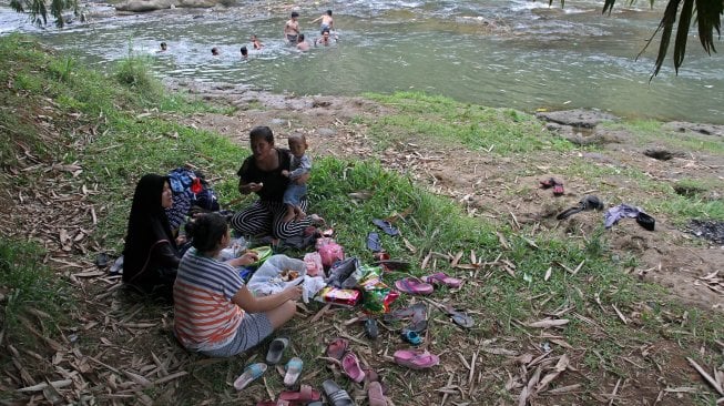 Sejumlah warga menikmati suasana sungai Ciliwung di kawasan Depok, Jawa Barat, Senin (1/7). [Suara.com/Arief Hermawan P]