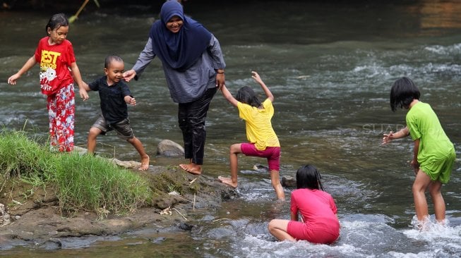 Sejumlah warga menikmati suasana sungai Ciliwung di kawasan Depok, Jawa Barat, Senin (1/7). [Suara.com/Arief Hermawan P]