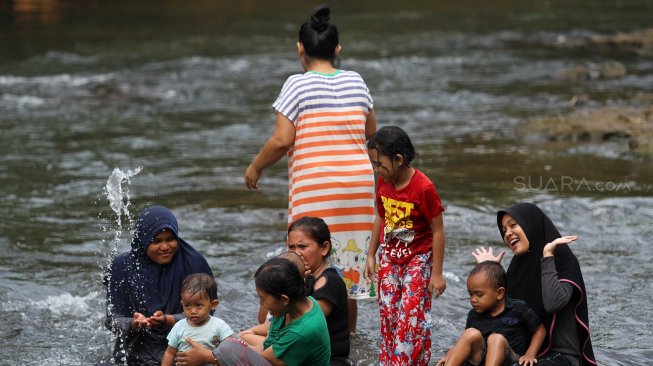 Sejumlah warga menikmati suasana sungai Ciliwung di kawasan Depok, Jawa Barat, Senin (1/7). [Suara.com/Arief Hermawan P]