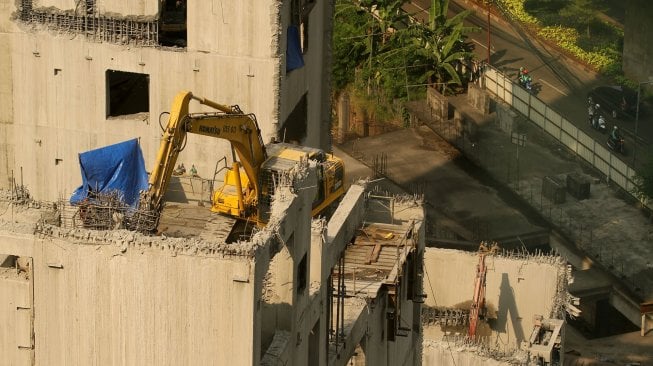 Alat berat beroperasi membongkar gedung yang mangkrak di jalan KH Mas Mansyur, Karet Tengsin, Jakarta, Selasa (7/2). [Suara.com/Arief Hermawan P]