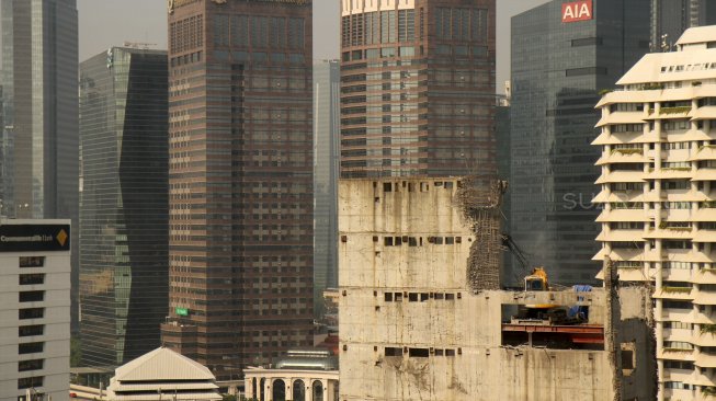 Alat berat beroperasi membongkar gedung yang mangkrak di jalan KH Mas Mansyur, Karet Tengsin, Jakarta, Selasa (7/2). [Suara.com/Arief Hermawan P]