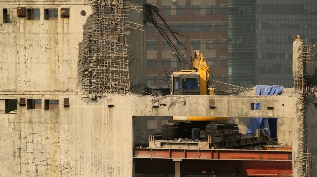 Alat berat beroperasi membongkar gedung yang mangkrak di jalan KH Mas Mansyur, Karet Tengsin, Jakarta, Selasa (7/2). [Suara.com/Arief Hermawan P]