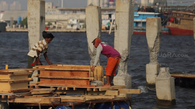 Pekerja menyelesaikan pembangunan dermaga dan pemecah ombak di kawasan Kampung Kerang Hijau, Muara Angke, Jakarta, Rabu (3/7). [Suara.com/Muhaimin A Untung]