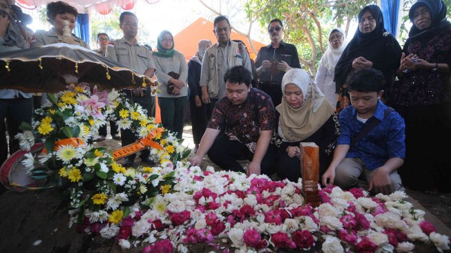 Istri dan dua anak Almarhum Kepala Pusat Data Informasi dan Humas Badan Nasional Penanggulangan Bencana (BNPB) Sutopo Purwo Nugroho, Retno Utami (tengah), Muhammad Ivanka Rizaldi Nugroho (kiri) dan Muhammad Aufa Wikantyasa Nugroho (kanan) berdoa di makam Sutopo di Tempat Pemakaman Umum Sonolayu, Boyolali, Jawa Tengah, Senin (8/7). ANTARA FOTO/Aloysius Jarot Nugroho