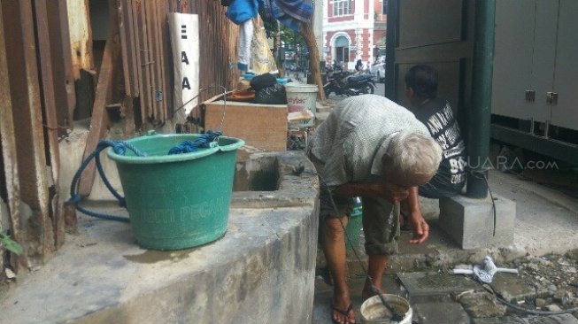 Sugianto (58), pengunjung Kota Lama Semarang, membasuh muka dan kakinya dengan air dari sumur tua bersejarah peninggalan penjajahan Belanda, Kamis (11/7/2019). [Suara.com/Adam Iyasa]