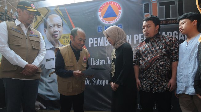 Kepala Badan Nasional Penanggulangan Bencana (BNPB) Letjen TNI Doni Monardo (kiri) bersama Ketua Dewan Pertimbangan Ikatan Jurnalis Televisi Indonesia (IJTI) Imam Wahyudi (kedua kiri) menyerahkan penghargaan "Pengabdian Tanpa Batas" kepada Almarhum Sutopo Purwo Nugroho yang diterima istri Retno Utami (tengah) di Boyolali, Jawa Tengah, Kamis (11/7). [ANTARA FOTO/Aloysius Jarot Nugroho]