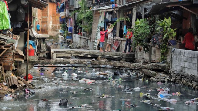 Warga beraktifitas di samping kali penuh sampai di kawasan kebon sirih, Jakarta, Minggu (14/7). [Suara.com/Muhaimin A Untung]