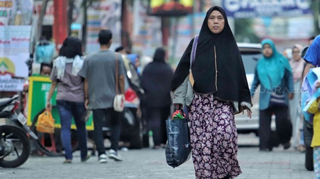 Warga membawa barang bawaan menggunakan tas plastik di Pasar Baru, Jakarta, Minggu (14/7). [Suara.com/Muhaimin A Untung]