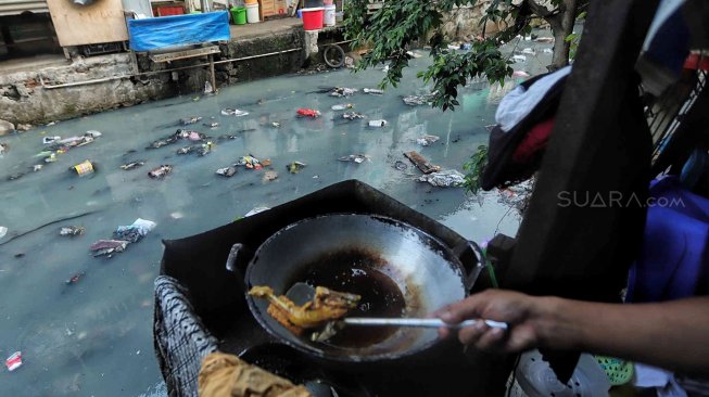 Warga beraktifitas di samping kali penuh sampai di kawasan kebon sirih, Jakarta, Minggu (14/7). [Suara.com/Muhaimin A Untung]