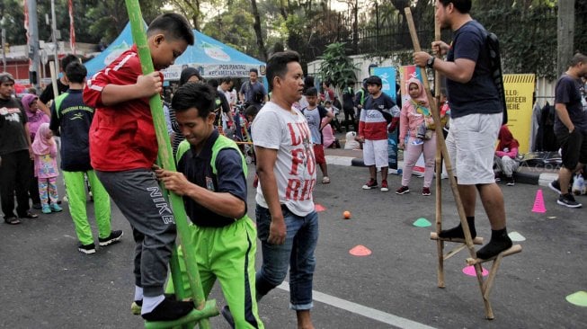 Penggerak Olahraga DKI Jakarta saat membimbing warga untuk mencoba permainan tradisional saat Hari Bebas Kendaraan Bermotor di Bundaran HI, Jakarta, Minggu (14/7). [Suara.com/Muhaimin A Untung]