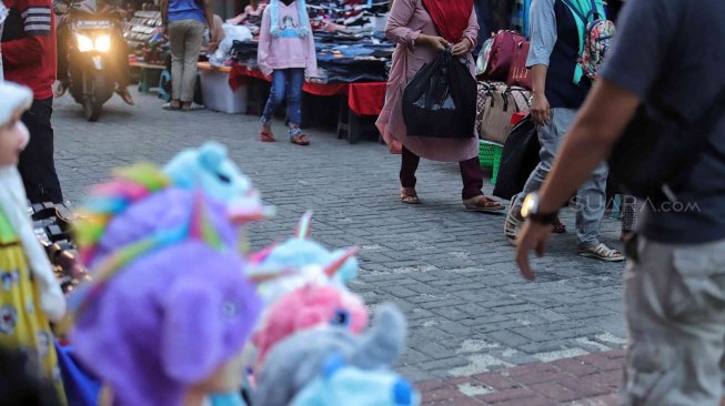 Warga membawa barang bawaan menggunakan tas plastik di Pasar Baru, Jakarta, Minggu (14/7). [Suara.com/Muhaimin A Untung]