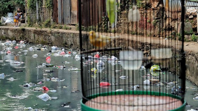 Warga beraktifitas di samping kali penuh sampai di kawasan kebon sirih, Jakarta, Minggu (14/7). [Suara.com/Muhaimin A Untung]