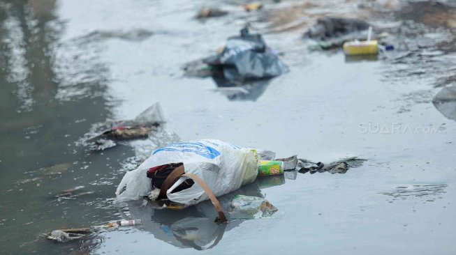 Warga beraktifitas di samping kali penuh sampai di kawasan kebon sirih, Jakarta, Minggu (14/7). [Suara.com/Muhaimin A Untung]