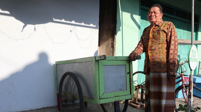 Samsuri bersama gerobak buburnya.