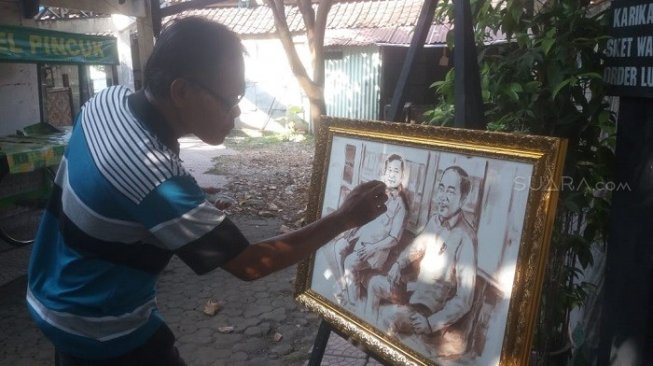 Kunarna tengah menyelesaikan lukisan sketsa Prabowo-Jokowi saat bertemu di MRT. (Suara.com/Ari P)