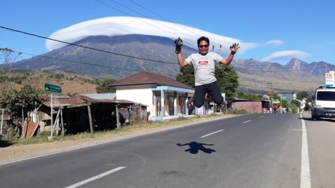 Warga berswafoto dengan latar belakang fenomena 'topi awan' Gunung Rinjani di Lombok, NTB, Rabu (17/7/2019). (Foto: Antara/Rosidin)