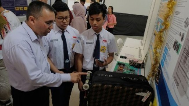 Seorang juri memeriksa karya siswa SMPN 3 Semarang yaitu alat pendeteksi kepemilikan koper melalui telepon genggam dalam pameran International Science and Invention di Denpasar, Bali, Sabtu (22/6/2019). Kegiatan yang memamerkan karya hasil penelitian tersebut diikuti 101 pelajar/mahasiswa se-Indonesia serta 46 pelajar/mahasiswa dari 10 negara [ANTARA FOTO/Nyoman Hendra Wibowo/nym/hp].