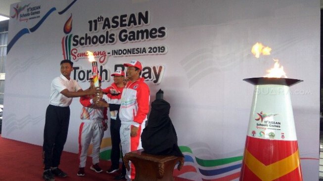 Wali Kota Semarang Hendrar Prihadi (kanan) menyerahkan api abadi Mrapen ke atlet Bayu Seno Aji untuk diarak menuju Holly Stadium guna dilakukan penyalaan api calderon tanda dimulainya gelaran ASEAN School Games 2019, Kamis (18/7). [Suara.com/Adam Iyasa]