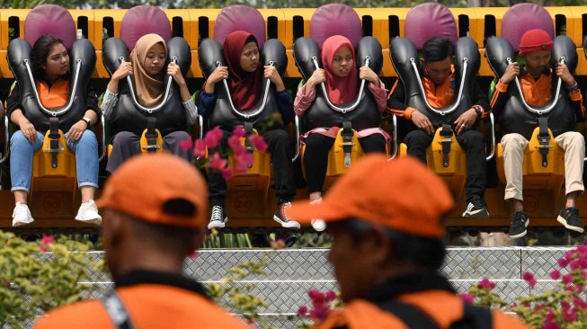 Dua petugas Penanganan Prasarana Sarana Umum (PPSU) DKI Jakarta mencoba wahana permainan saat berwisata di Dufan, Ancol, Jakarta, Senin (22/7). ANTARA FOTO/Wahyu Putro A