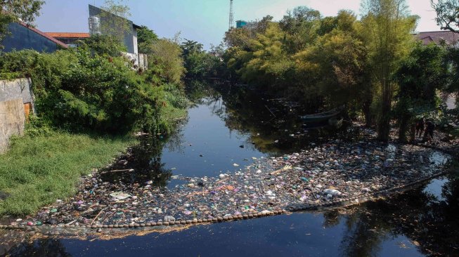 Petugas Dinas Lingkungan Hidup (DLH) membersihkan sampah di sekitaran Sungai Loji yang berwarna hitam akibat pencemaran limbah batik di Pekalongan, Jawa Tengah, Selasa (23/7). ANTARA FOTO/Harviyan Perdana Putra