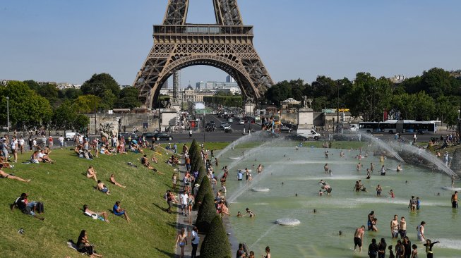 Sekumpulan warga Paris dan turis berendam di kolam Trocadero Fountains di dekat menara Eiffel, Paris, Perancis, Kamis (25/7). [Bertrand Guay/AFP]